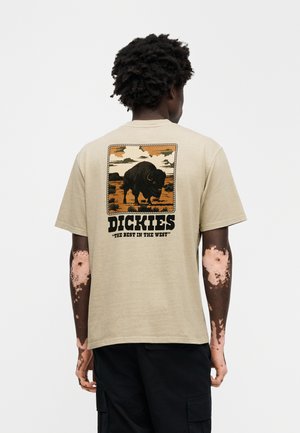Tricou din bumbac bej, cu un grafic cu un bizon pe fundal de peisaj, cu textul "DICKIES" și "THE BEST IN THE WEST" în negru îndrăzneț.