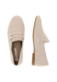 Mocassini in pelle scamosciata beige con suola piatta in gomma bassa. Presentano una fascia decorativa sulla tomaia e dettagli di cucitura lungo la parte superiore.