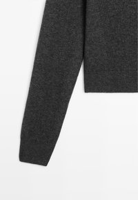 Pull en maille gris foncé à manches longues, manches et ourlet côtelés, présenté sur fond blanc.