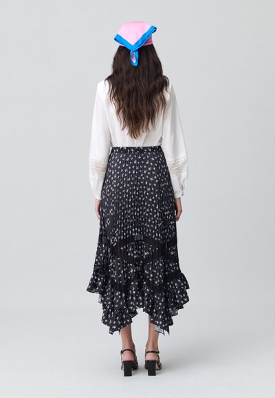 Falda negra plisada con estampados florales blancos, volantes en capas y un panel transparente. Blusa blanca de manga larga con puños detallados, pañuelo rosa y azul en la cabeza.