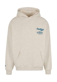 Sudadera con capucha color beige claro hecha de tela suave. Cuenta con un bolsillo tipo canguro en la parte frontal y texto/logo azul en el pecho y la manga.