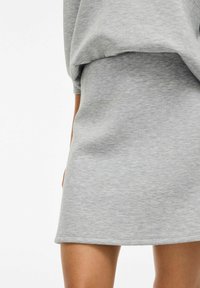 Jupe en coton gris avec une texture lisse, présentant un design ajusté et une taille élastique, se terminant au-dessus du genou.