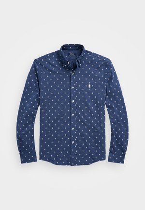 Chemise bleu marine à manches longues, boutonnée, avec motif losanges blancs et petit logo cheval blanc sur la poitrine.