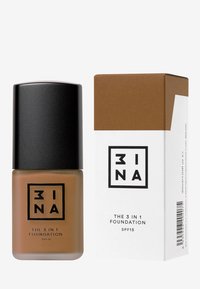 Botella de vidrio marrón con una tapa negra, etiquetada con "3INA THE 3 IN 1 FOUNDATION SPF15". Acompañada de una caja mate con un diseño marrón y blanco.