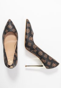 Escarpins noirs à talons hauts avec bouts pointus, présentant une surface texturée et un motif marron. Accents dorés sur les talons.