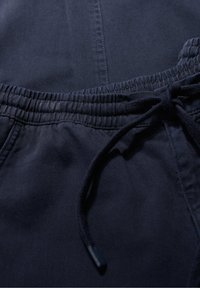 Pantaloni joggers din bumbac de culoare albastru marin, cu talie elastică, închidere cu șnur și textură subtilă. Prezintă material plisat de-a lungul liniei taliei.