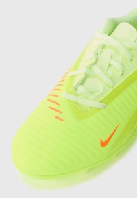 Nærbilde av neongul-grønn fotballsko med hvite snører og liten oransje Nike-logo på siden.