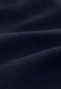 Navy blue textured fabric with a subtle weave pattern, showing creases and folds, creating depth and dimension. Soft finish.