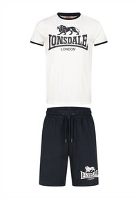 Valkoinen puuvillapaita mustilla yksityiskohdilla, jossa on leijonalogot ja "Lonsdale London" -teksti; paritettu tummansinisien shortsien kanssa, joissa on samanlainen logo.
