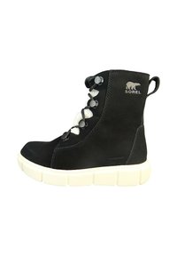 Czarne wodoodporne buty z białym futerkiem wewnątrz, z okrągłym noskiem, sznurowanym zapięciem oraz grubą białą gumową podeszwą z rowkowanym detalem.
