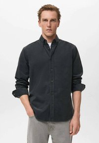 Camisa abotonada gris oscuro de tela suave, con collar clásico, mangas largas arremangadas hasta los codos y cierre frontal con botones.