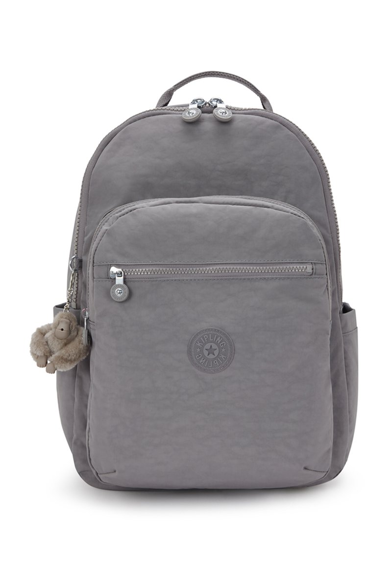 Grå Kipling ryggsäck med ficka med dragkedja fram, sidofickor, handtag ovanpå och en liten plyschapa nyckelring fäst.