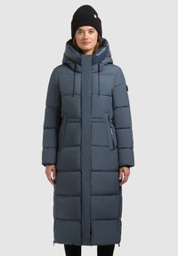 Lang, fyldig jakke i mørkeblå med høj krave, snørejusterbar hætte og sidelommer; har en glat, blank finish og vandrette søm.