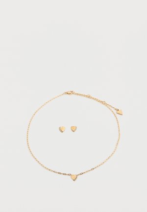 Σετ κοσμημάτων σε χρυσό χρώμα που περιλαμβάνει βραχιόλι αλυσίδα με μενταγιόν καρδιά και αντίστοιχα σκουλαρίκια καρδιά, διακοσμημένα με μικρές πέτρες.