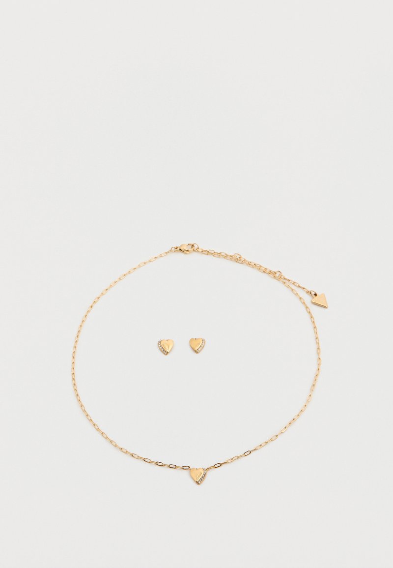 Σετ κοσμημάτων σε χρυσό χρώμα που περιλαμβάνει βραχιόλι αλυσίδα με μενταγιόν καρδιά και αντίστοιχα σκουλαρίκια καρδιά, διακοσμημένα με μικρές πέτρες.