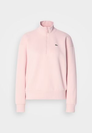 Lyserosa kvart-zip hettegenser med lange ermer, høy krage, ribbede mansjetter og hem, og en liten grønn krokodillelogo på brystet.