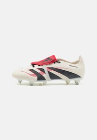 White soccer cleat with red accents, black stripes, and a textured finish. Features a streamlined design and a secure lace system.
