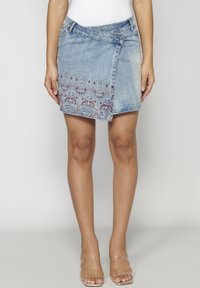 Denim mini krilo z asimetričnim dizajnom, svetlo modrim pranjem, okrašeno s cvetnim vezenjem v rdeči in modri barvi na robu.