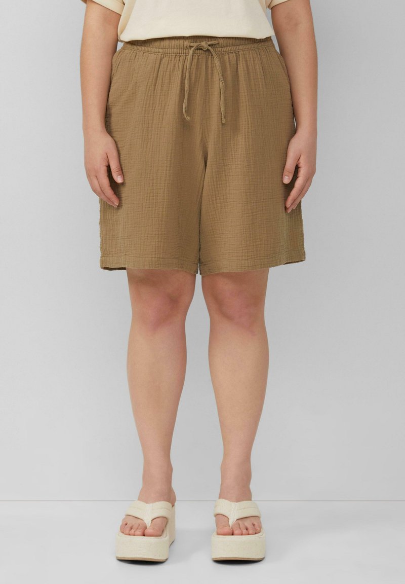 Bruine, gestructureerde shorts met een elastische tailleband en een trekkoord. Gecombineerd met off-white platform sandalen.