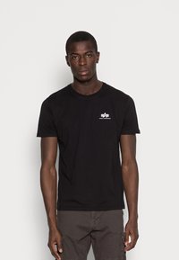 Tricou din bumbac negru cu guler rotund și mâneci scurte. Prezintă un mic logo alb pe partea stângă a pieptului. Textură netedă.