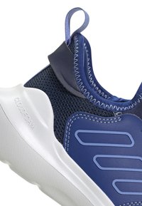 Zapatilla deportiva azul con parte superior de malla, acentos de piel suave, suela blanca y una lengüeta en el talón; presenta un diseño texturizado y duradero.