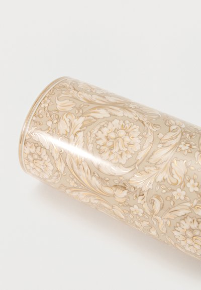 Vase cylindrique à motif floral baroque crème et or sur fond blanc, présenté tourné sur le côté.