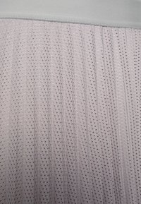 Lila stof met verticale plooien en een nettextuur, voorzien van een gladde grijze tailleband. Kleine, gelijkmatig verspreide uitsparingen zijn zichtbaar.