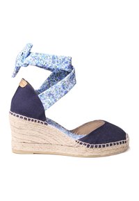Alpargatas de cuña de lona azul con tira de tobillo de estampado floral. Suela de yute trenzado y punta redondeada. Costuras de contraste a lo largo del borde.