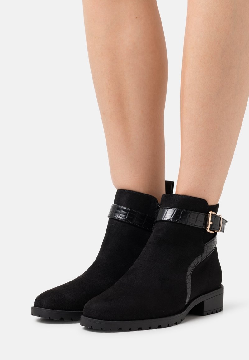 Černé semišové kotníkové boty s texturovaným páskem z lakované kůže a detailem s přezkou, s masivní podrážkou a designem zaoblené špičky.