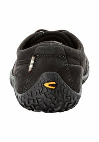 Schwarze Wildleder-Schuhe mit einer strukturierten Gummisohle, die ein markantes gelbes Logo und eine graue Außensohle mit strukturiertem Profil aufweist.