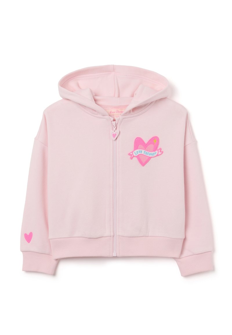 Sudadera de cremallera en rosa claro con un diseño de corazón en el pecho, el texto "Love Therapy" y un pequeño corazón en una manga. Tejido suave.