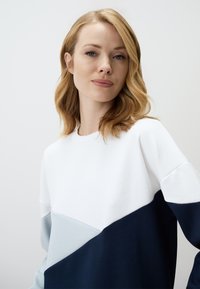 Crewneck sweatshirt met een kleurblokontwerp in wit, lichtblauw en marineblauw. Gemaakt van zachte stof met een gladde textuur.