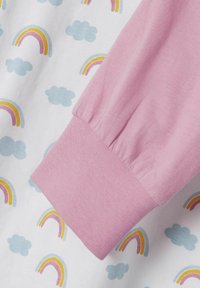 Chemise à manches longues avec un poignet rose doux, en tissu blanc orné de motifs répétés de nuages bleus et de arcs-en-ciel colorés.