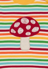 Gestreiftes Shirt in Rot, Gelb, Grün und Blau, mit einer roten Pilz-Applikation mit weißen Punkten im Brustbereich. Baumwollstoff.