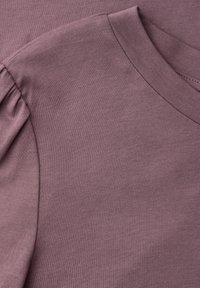 Mauve strikket stof med ribbet rund halsudskæring og detaljer med opsamlet pufærme på et beklædningsstykke.