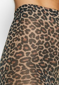 Gjennomsiktige leggings med et leopardmønster som har svarte og brune flekker på en beige bakgrunn; glatt tekstur og elastisk midjebånd.