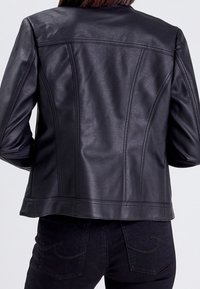 Veste en cuir noir avec coutures structurées, dos droit et quincaillerie minimale. Texture lisse, coupe ajustée et absence de fermetures visibles.