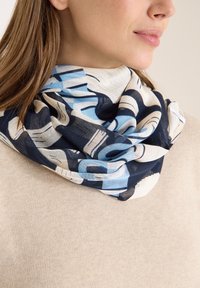 Modrý a krémový šátek s abstraktním vzorem z lehké látky, volně přehozený kolem krku, s abstraktními tvary a jemnou texturou.