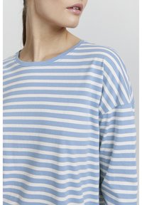 Hosszú ujjú ing világoskék és fehér vízszintes csíkokkal. Puha pamut anyag, kerek nyakkivágással és lazább fazonnal. Látható varrási részletek.