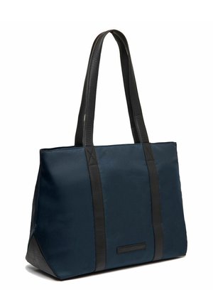 Sac fourre-tout en tissu bleu marine avec des accents en cuir noir, grand ouvert en haut, deux poignées plates, et une finition texturée sur la base.