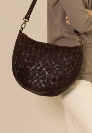 Braune Lederhandtasche mit geflochtenem Design, runder Form und Messingbeschlägen. Die Tasche hat einen langen Schultergurt für einen einfachen Transport.