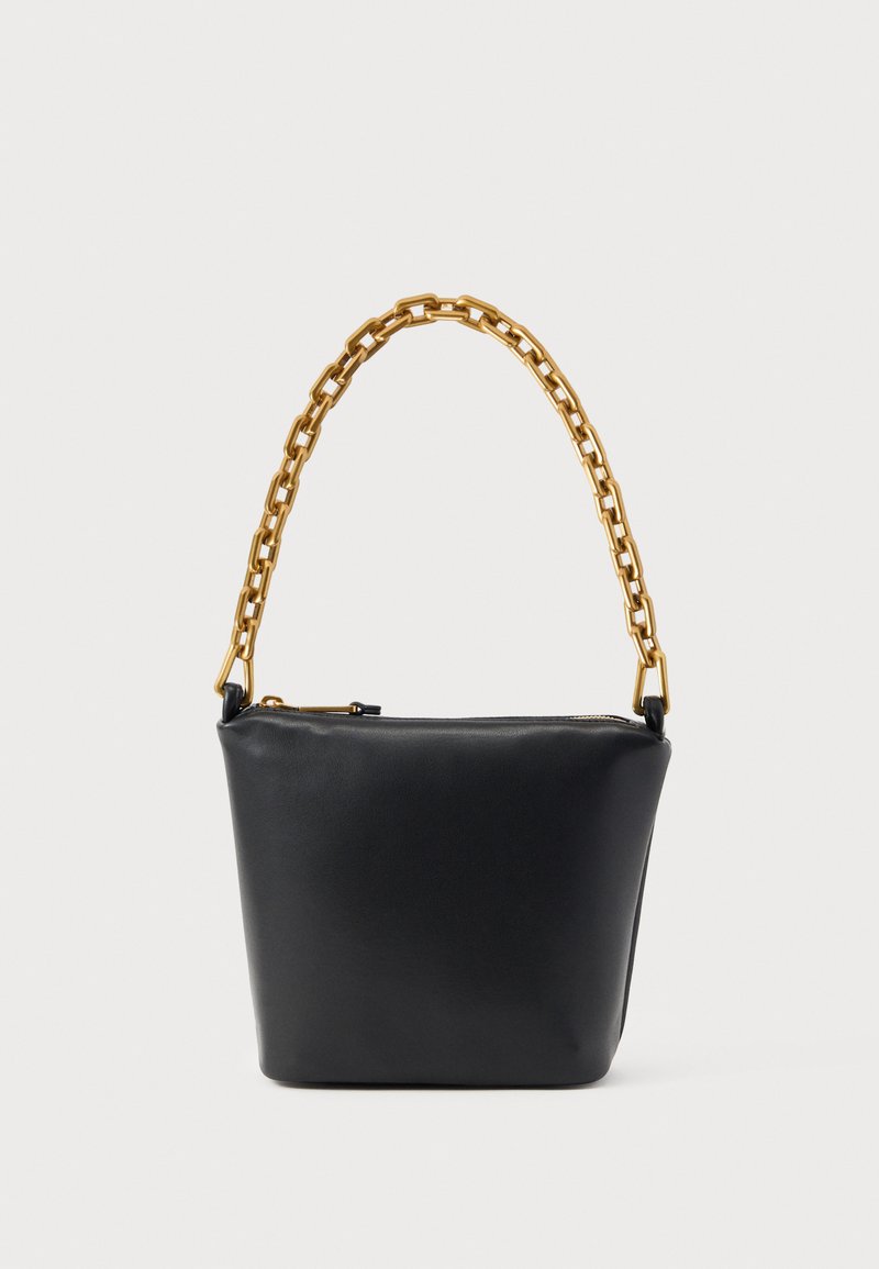 Μαύρη δερμάτινη τσάντα με χρυσή αλυσίδα και πάνω φερμουάρ, τοποθετημένη σε απλό φωτεινό φόντο.