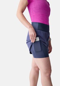 Marineblaue Sportshorts mit hohem Bund, versehen mit einer Seitentasche für ein Smartphone. Das Oberteil ist ein leuchtend pinkes, kurzärmliges T-Shirt.
