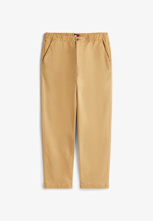 Bēša ikdienas bikses ar elastīgu vidukli, priekšpusē poga, rāvējslēdzējs un šķērseniski kabatas, novietotas uz balta fona.