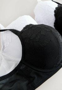 Les soutiens-gorge noirs et blancs présentent une superposition en dentelle et un tissu lisse, avec une combinaison de mesh et de matière unie, des bonnets structurés et des bretelles réglables.