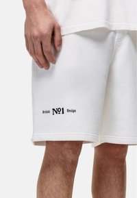 Witte katoenen shorts met een geribde tailleband, zijzakken en geborduurd "British No1 Design" in het zwart op het linkerbeen.