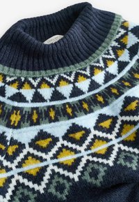 Adīts džemperis ar ribotu tumši zilu apkakli, kas ir rotāta ar ģeometriskām rakstām dzeltenā, zaļā un gaiši zilā krāsā uz tumša fona.