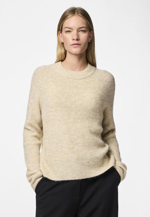 Beige strikkegenser med ribbestruktur, rund hals og lange ermer. Stoffet ser mykt og litt bustete ut, og gir en avslappet passform.