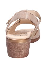 Beige Sandale mit verstellbaren Riemen, strukturierten goldenen Akzenten und einem niedrigen Absatz. Das glatte Innenfutter und die gemusterte Sohle bieten Komfort.