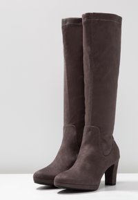 Botas altas de ante gris con puntera redonda, tacón sólido y detalle de costura limpia. Textura suave con una silueta entallada.